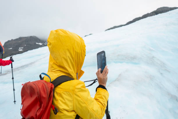 istock Woman taking photos of the glacier using smartphone on the Exit Glacier. Unrecognizable people hiking in the background. Kenai Fjords National Park. Alaska. 2077392930