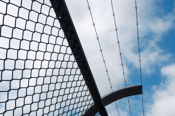 Close-up on a barbed wire fence with an overcast sky.