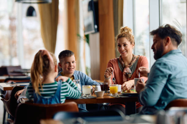 istock Happy family eating breakfast at dining table in hotel restaurant. 2077442685