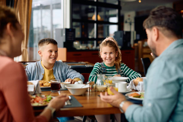 istock Happy kids talking to their parents while having breakfast in hotel restaurant. 2077444898