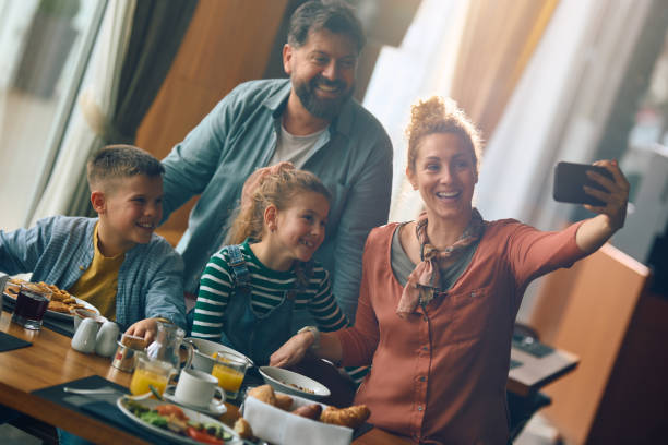 istock Happy family taking selfie while having breakfast in restaurant during their hotel stay. 2077445414