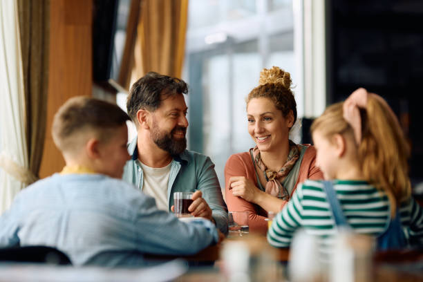 Happy family talking while eating at dining table in a restaurant.