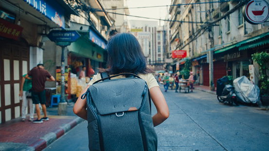Young Asian woman backpacker walking along on the street at Bangkok, Thailand. Holiday vacation trip concept.