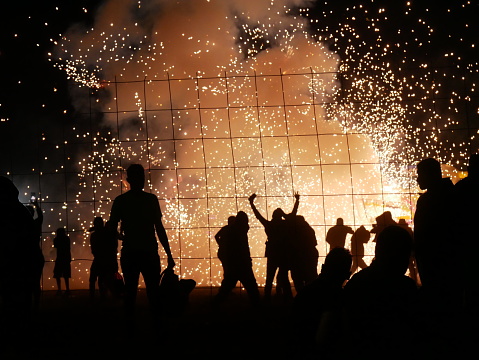 Tultepec, Mexico – March 09, 2024: Silhouetted individuals mesmerized by vibrant fireworks at night