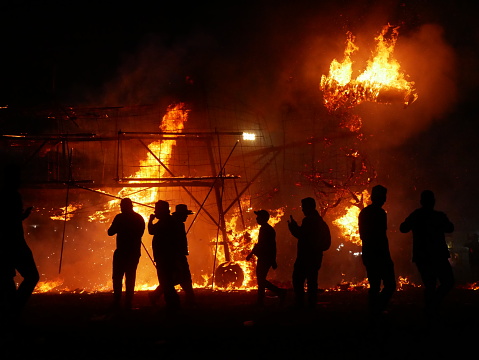 Tultepec, Mexico – March 09, 2024: A building engulfed in flames at night, with onlookers nearby
