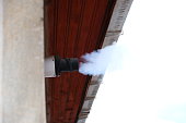Water vapor from a gas central heating boiler flue condenses in cold air. The flue vents through the exterior wall of a building. Gas boiler chimney in winter time