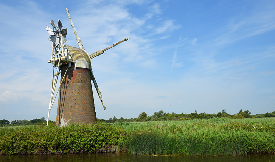Abandoned Windmill next to the river Ant Norfolk broads blue sky