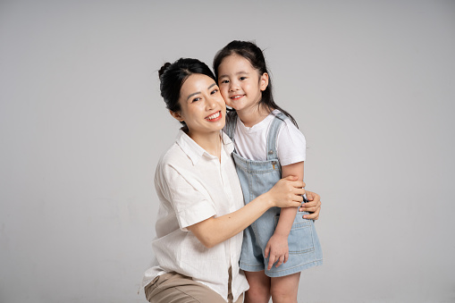 Portrait of an Asian mother and daughter posing on a white background