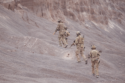Soldiers in camouflage military uniforms carrying weapons, Reconnaissance missions in rugged mountains, Assault infantry battle training.