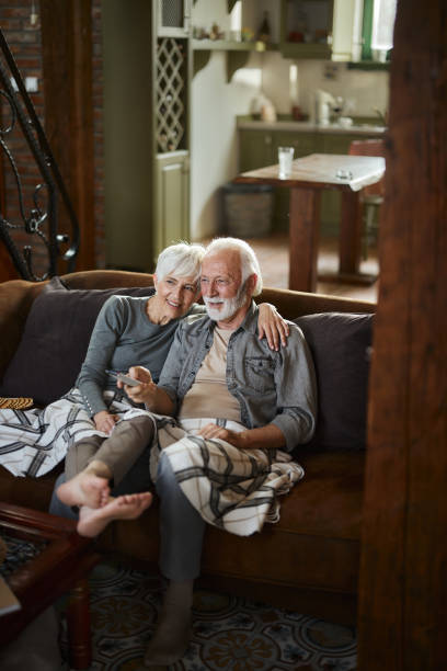 istock Happy mature couple watching TV on sofa at home. 2077515410