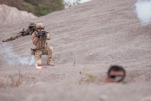 Soldiers in camouflage military uniforms carrying weapons, Reconnaissance missions in rugged mountains, Assault infantry battle training.