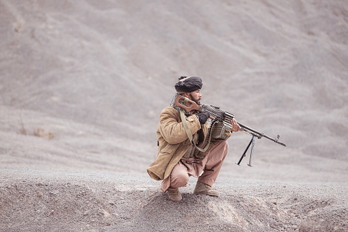 A Taliban soldier with a machine gun, In the desert mountain landscape