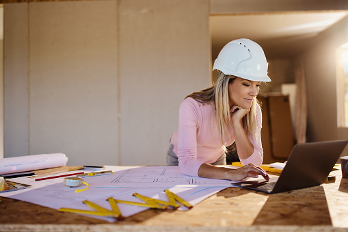Female building contractor working on a computer at construction site. Copy space.