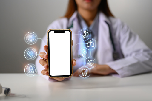 Female doctor showing smartphone with medical icons. Telemedicine Concept.