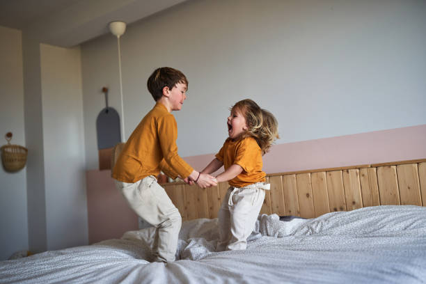 istock Siblings playing and jumping on parents bedroom 2077560627