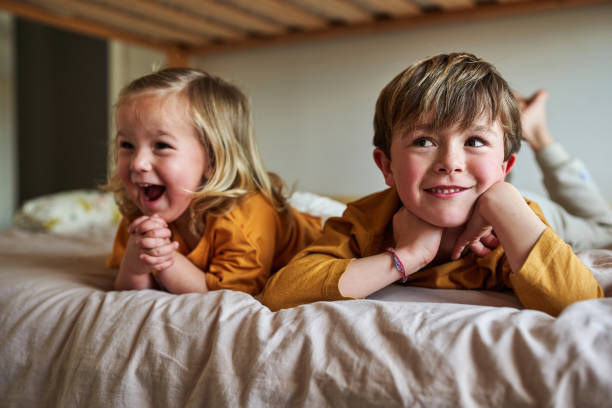 istock Happy siblings lying down on their bed, laughing and having fun. 2077560629