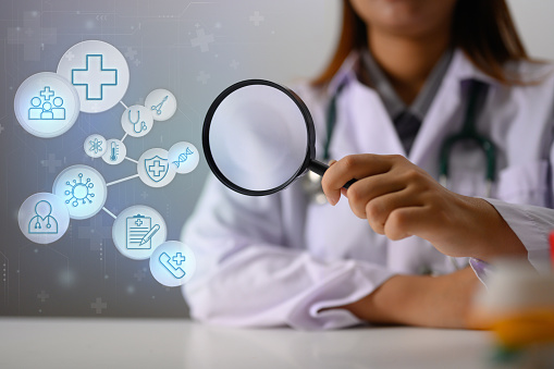 Doctor holding magnifying glass with medical and healthcare Icons. Medical check up concept.