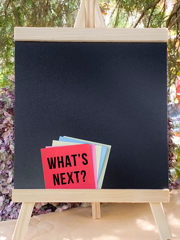 What's Next? text on notepaper with blackboard with copy space background. Business Concept.