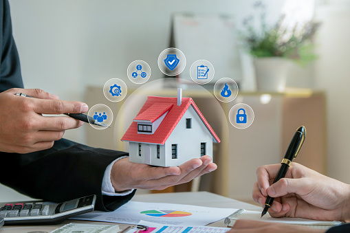 Man insurance agent holding house model with home insurance icon. Property insurance security concept to protect family, real estate from accidents and unexpected disaster.