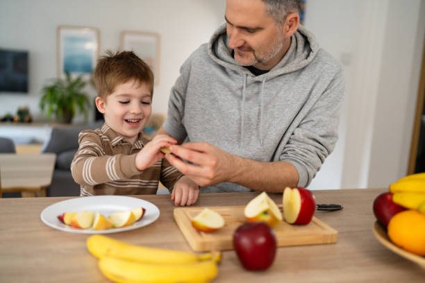 istock Dad and son eating fruit together at home 2077634615