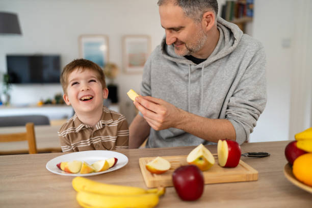 istock Dad and son eating fruit together at home 2077634616