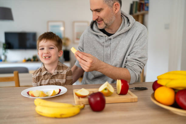 istock Dad and son eating fruit together at home 2077635177