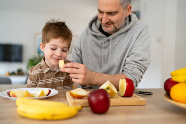 istock Dad and son eating fruit together at home 2077635184