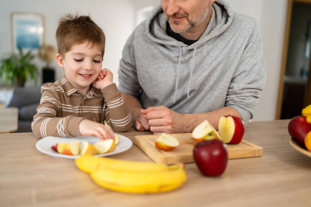 istock Dad and son eating fruit together at home 2077635741