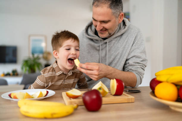 istock Dad and son eating fruit together at home 2077635792