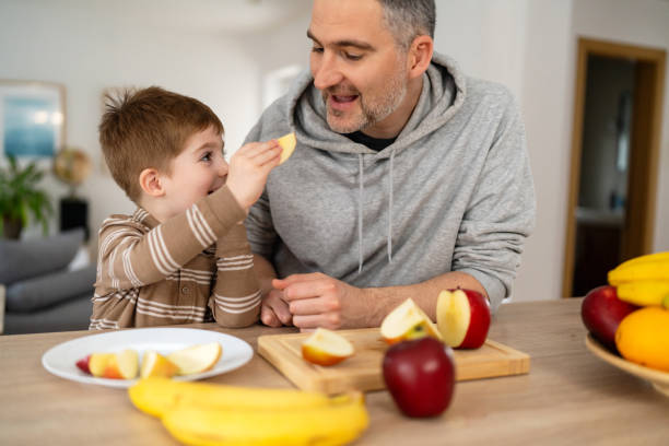 istock Dad and son eating fruit together at home 2077636339