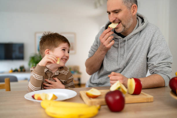 istock Dad and son eating fruit together at home 2077637396