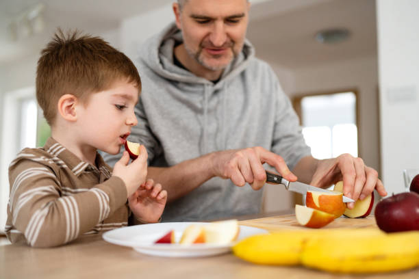 istock Dad and son eating fruit together at home 2077637410
