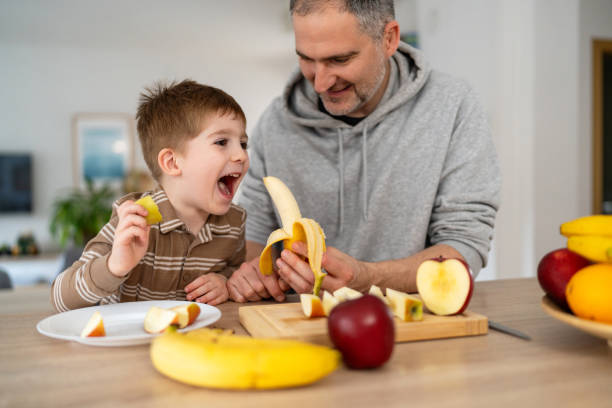 istock Dad and son eating fruit together at home 2077638465