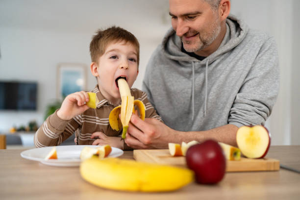 istock Dad and son eating fruit together at home 2077638979