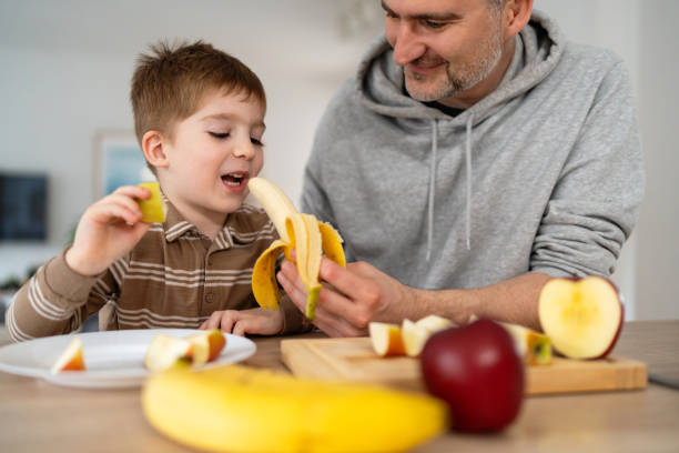 istock Dad and son eating fruit together at home 2077639507