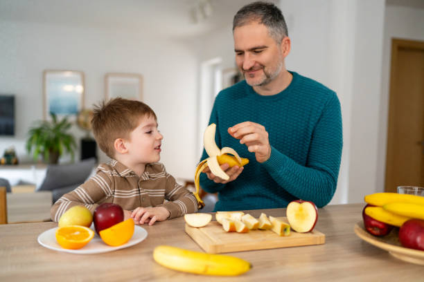 istock Dad and son eating fruit together at home 2077642652
