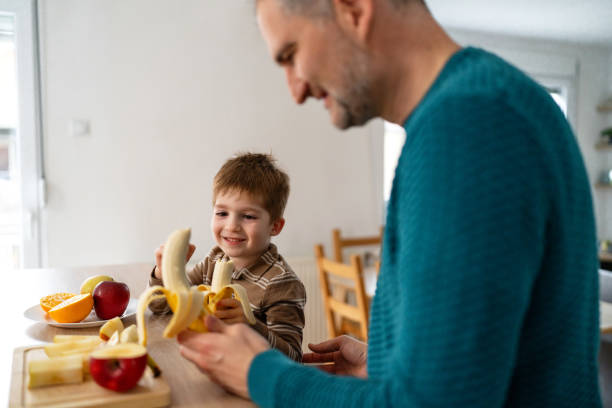 istock Dad and son eating fruit together at home 2077644736
