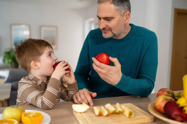 istock Dad and son eating fruit together at home 2077645779