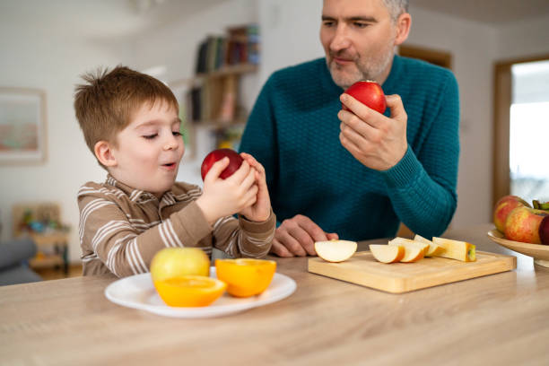 istock Dad and son eating fruit together at home 2077646293