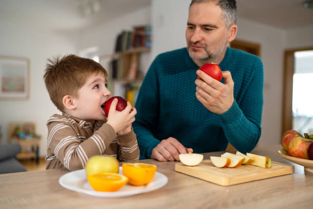 istock Dad and son eating fruit together at home 2077646317