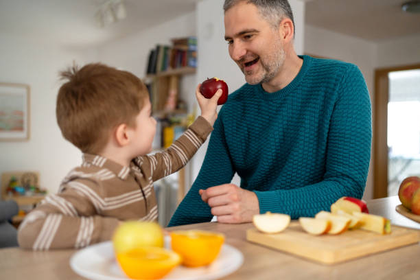 istock Dad and son eating fruit together at home 2077648983