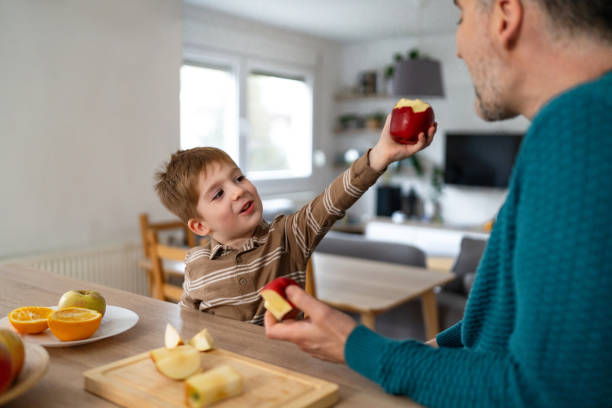 istock Dad and son eating fruit together at home 2077652123