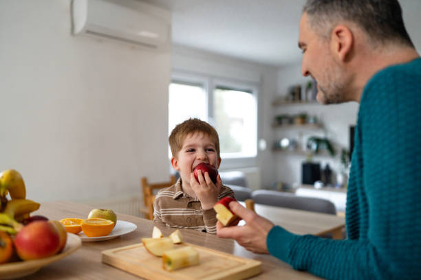 istock Dad and son eating fruit together at home 2077653692