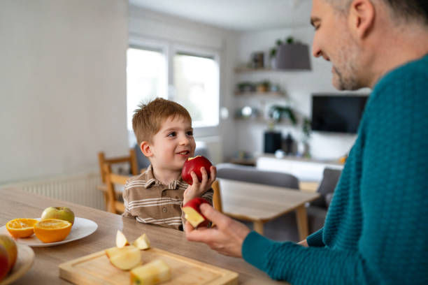 istock Dad and son eating fruit together at home 2077654224