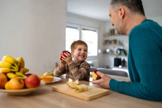 istock Dad and son eating fruit together at home 2077655309