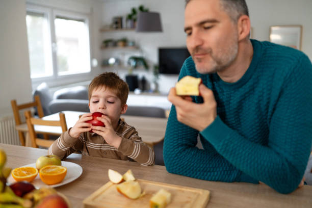 istock Dad and son eating fruit together at home 2077655835