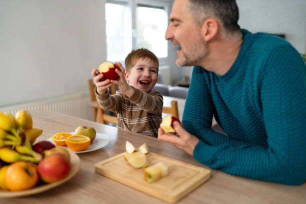 istock Dad and son eating fruit together at home 2077656352