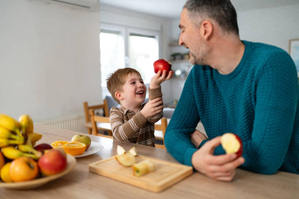 istock Dad and son eating fruit together at home 2077657387