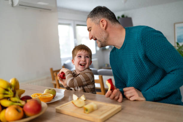 istock Dad and son eating fruit together at home 2077657397