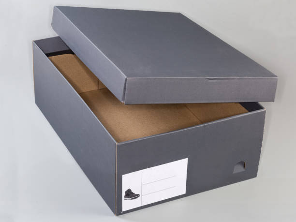 Empty dark gray cardboard shoes box with partly open lid on a light gray background